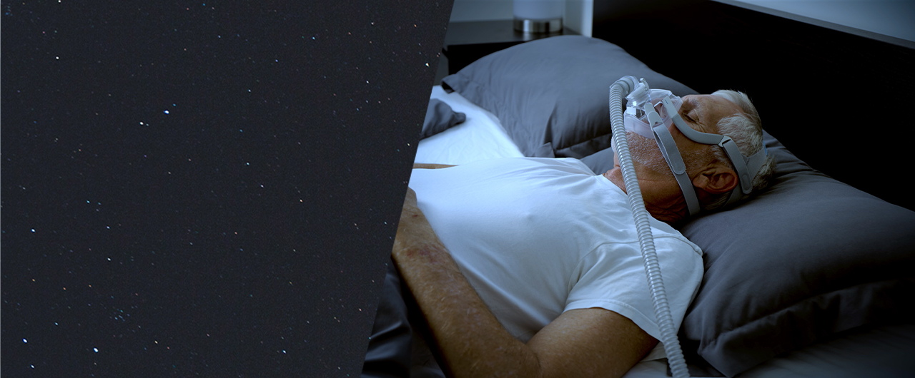 Man sleeping in bed wearing sleep apnea mask