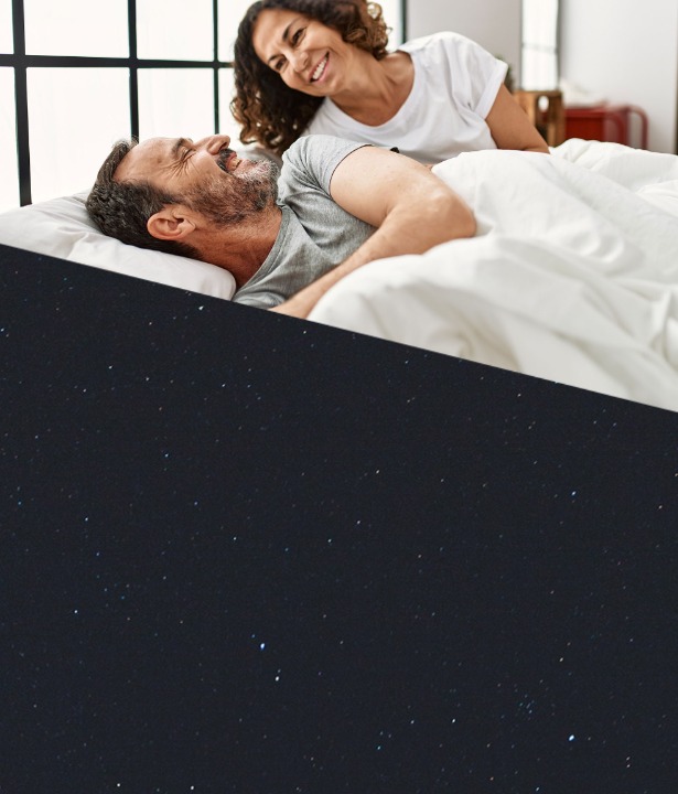 Couple smiling at each other as they wakeup from a restful nights sleep